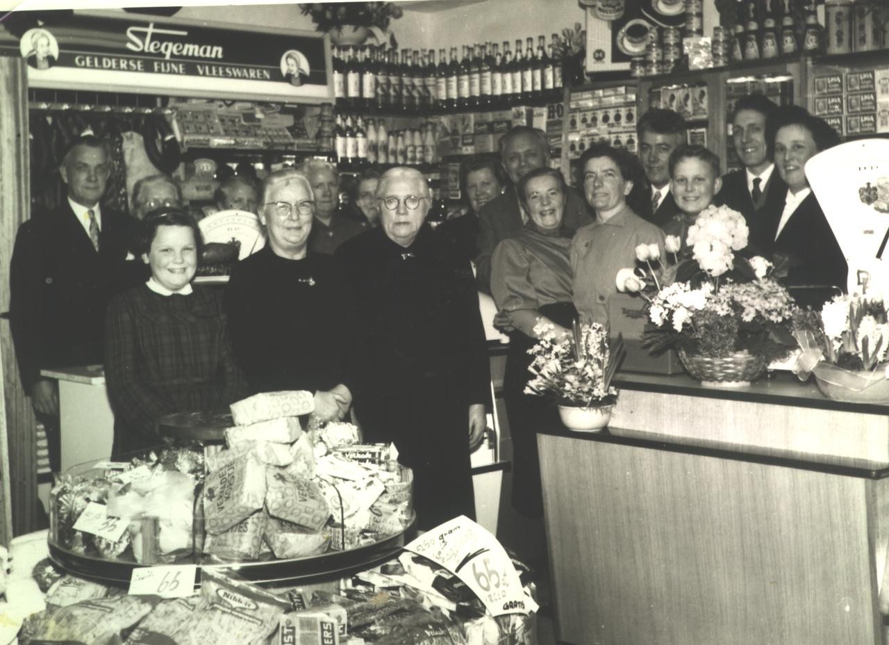 Bij de opening van de winkel aan de Jan Steenlaan. Van links naar rechts op de achtergrond: Jacob, Johanna, Jannetje, Stefie, Aaltje, Bep, Rijk, Jan en Wim en op de voorgrond van links naar rechts: Jeannette, oma Van de Lustgraaf, opoe Slok, Tho, Alie, Jan en Riek